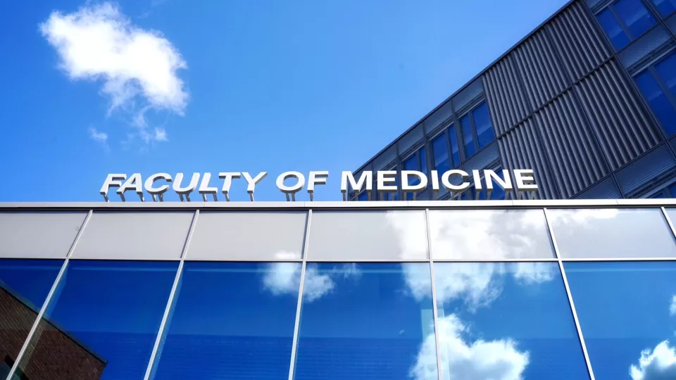 Sign on top of building, Faculty of Medicine, and blue sky. Photo.