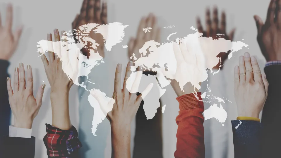 Hands in the air with world map double exposed on top. Photo montage.