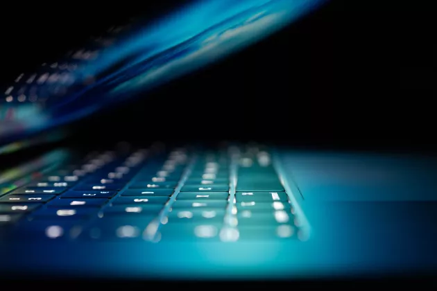 Laptop keyboard in blue light. Photograph.