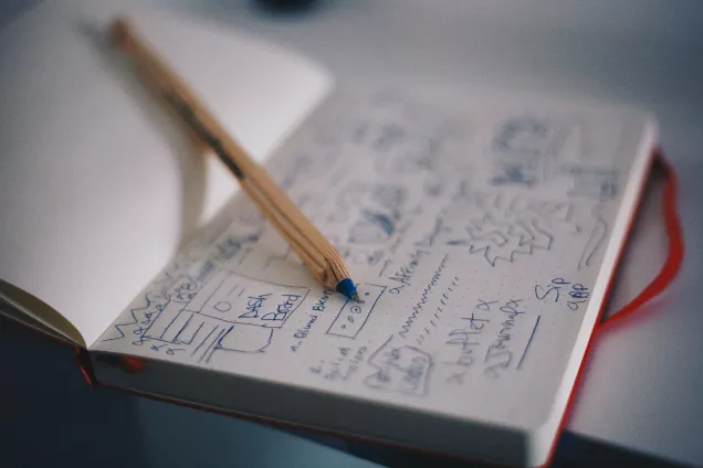 The image shows an open notebook with a pen lying on one side.