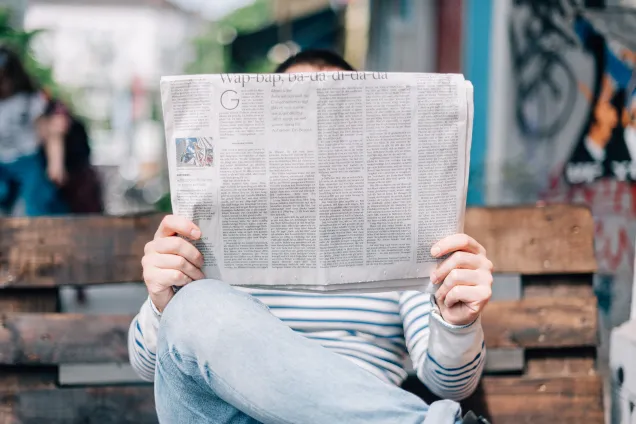 Person reading a newspaper. Photograph.