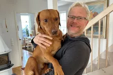 Tomas Deierborg in his home with his dog Malte in his arms.