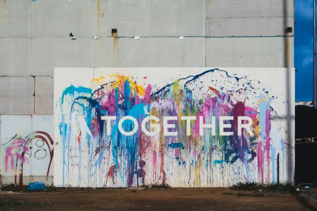 Big wall splashed with colours and the letters forming "Together" in front.