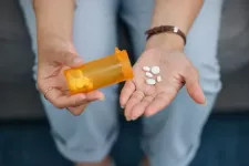 Vita piller hälls ur en gul burk i en hand. Foto. 
