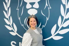 Cecilia Eriksson standing in front of the Sjölin´s School´s logotype